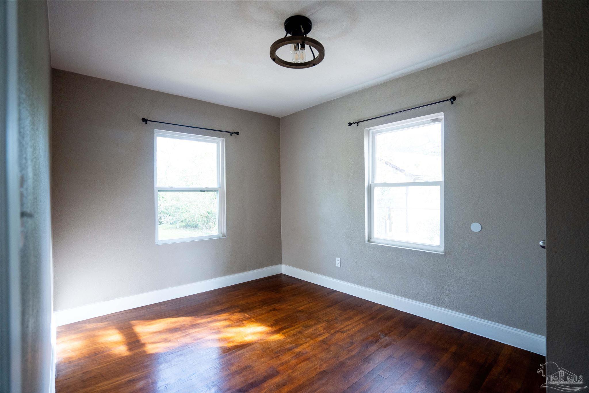 409 Frisco Road Pensacola, FL 32507 - Photo 11 of 27 a view of an empty room with wooden floor and window