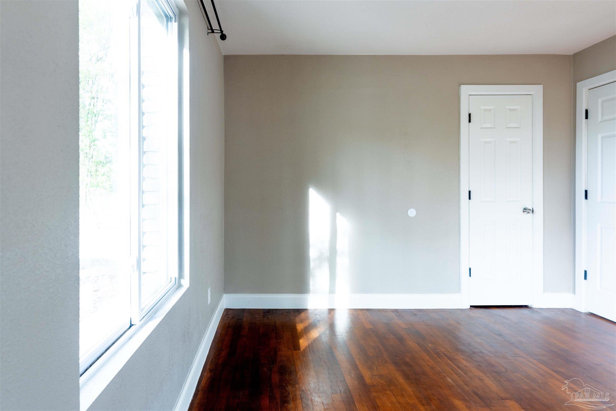 409 Frisco Road Pensacola, FL 32507 - Photo 12 of 27 a view of an empty room with wooden floor and a window