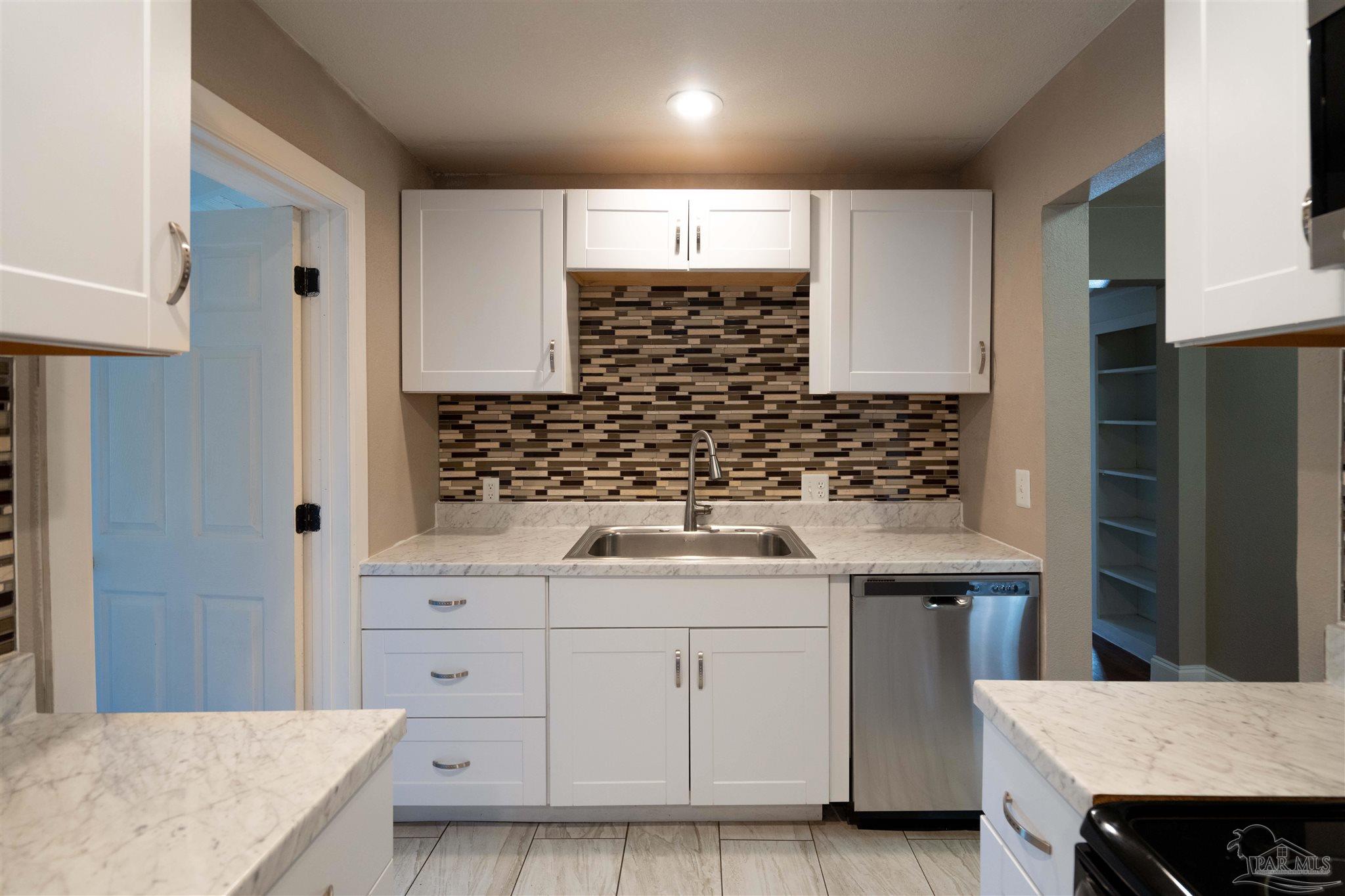 409 Frisco Road Pensacola, FL 32507 - Photo 5 of 27 a kitchen with white cabinets a sink and white appliances