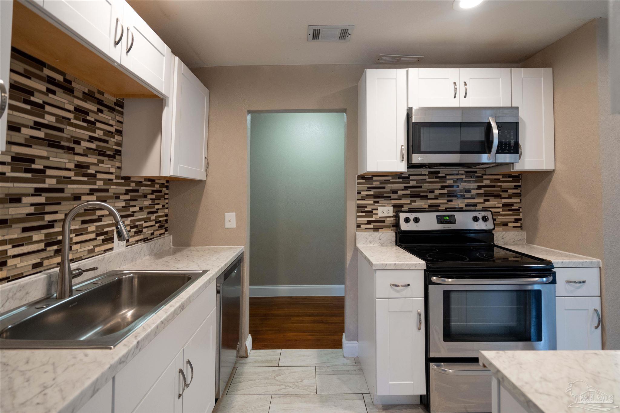 409 Frisco Road Pensacola, FL 32507 - Photo 7 of 27 a kitchen with granite countertop a stove and a sink