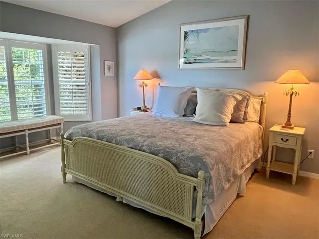 a spacious bedroom with a bed and a lamp on table