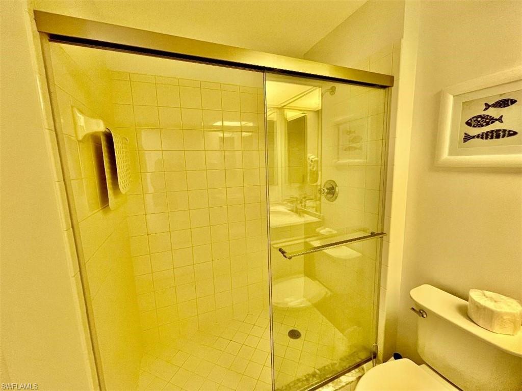 8380 Mystic Greens Way, Unit 1303 Naples, FL 34113 - Photo 18 of 25 a bathroom with a blue shower curtain