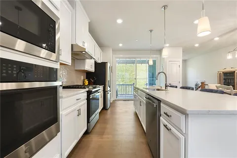 a large kitchen with stainless steel appliances kitchen island a large counter tops a stove a sink and a refrigerator