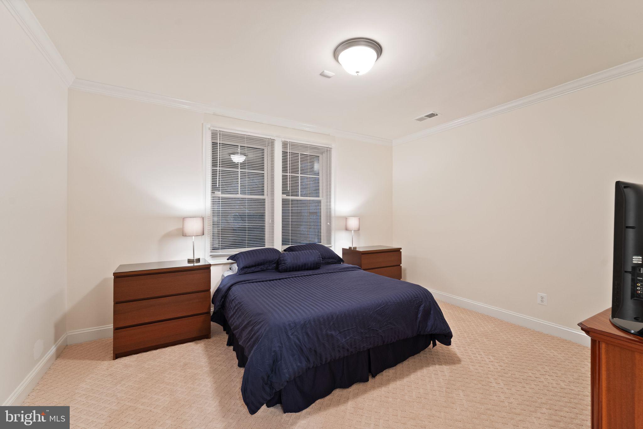9603 Thistle Ridge Lane Vienna, VA 22182 - Photo 59 of 73 a bedroom with a bed and a flat tv screen on a dresser