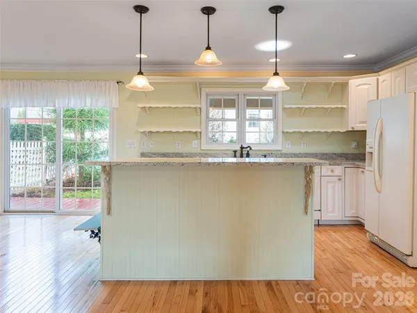 a kitchen with stainless steel appliances granite countertop a refrigerator a sink dishwasher a stove and white countertops with wooden floor