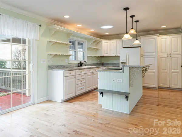 a kitchen with kitchen island a sink a stove a refrigerator and white cabinets
