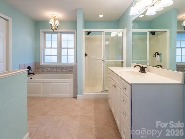 a bathroom with a double vanity sink a mirror a bathtub and next to a window