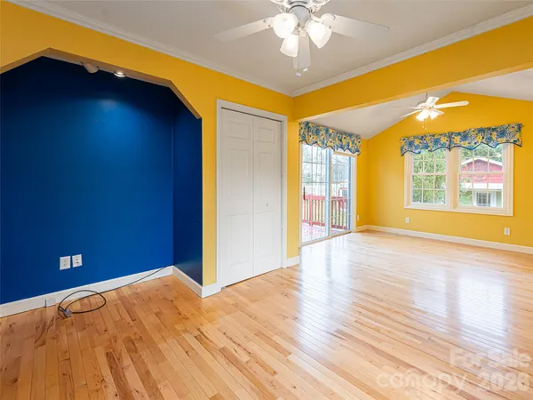 a view of an empty room with window and wooden floor