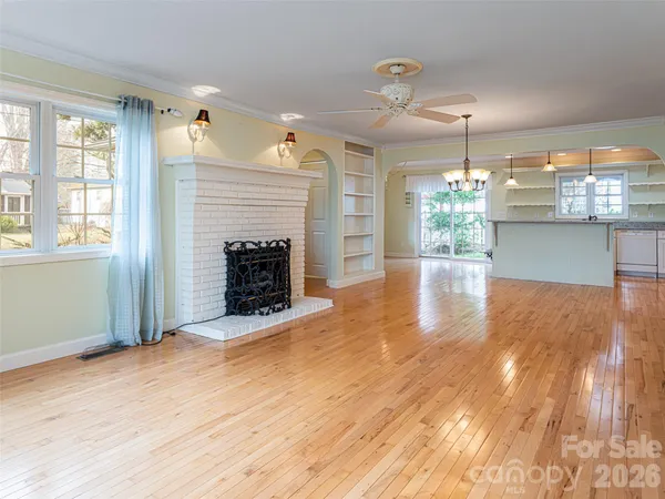 an empty room with wooden floor fireplace and chandelier