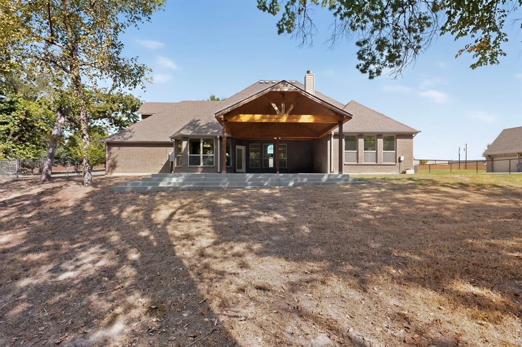 108 Winding Way Azle, TX 76020 - Photo 34 of 38 Brick exterior featuring a covered patio with exposed wood beams, a shingled roof, a stepped concrete patio, and multiple windows