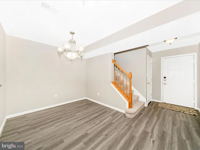 a view of a hallway with wooden floor and chandelier