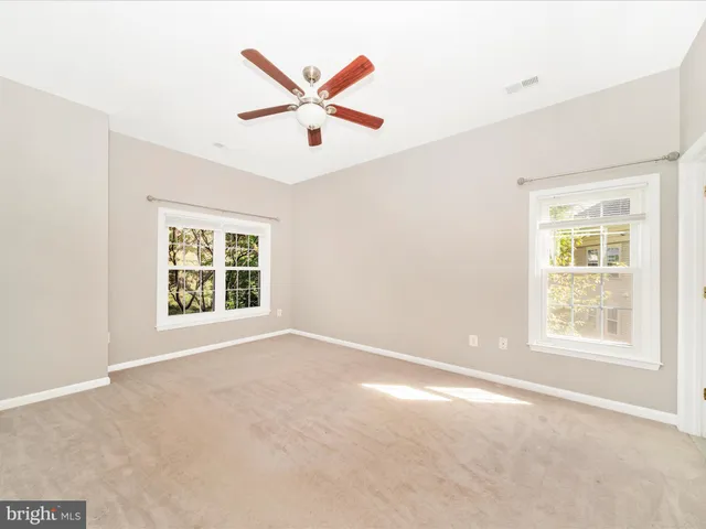 an empty room with ceiling fan and window