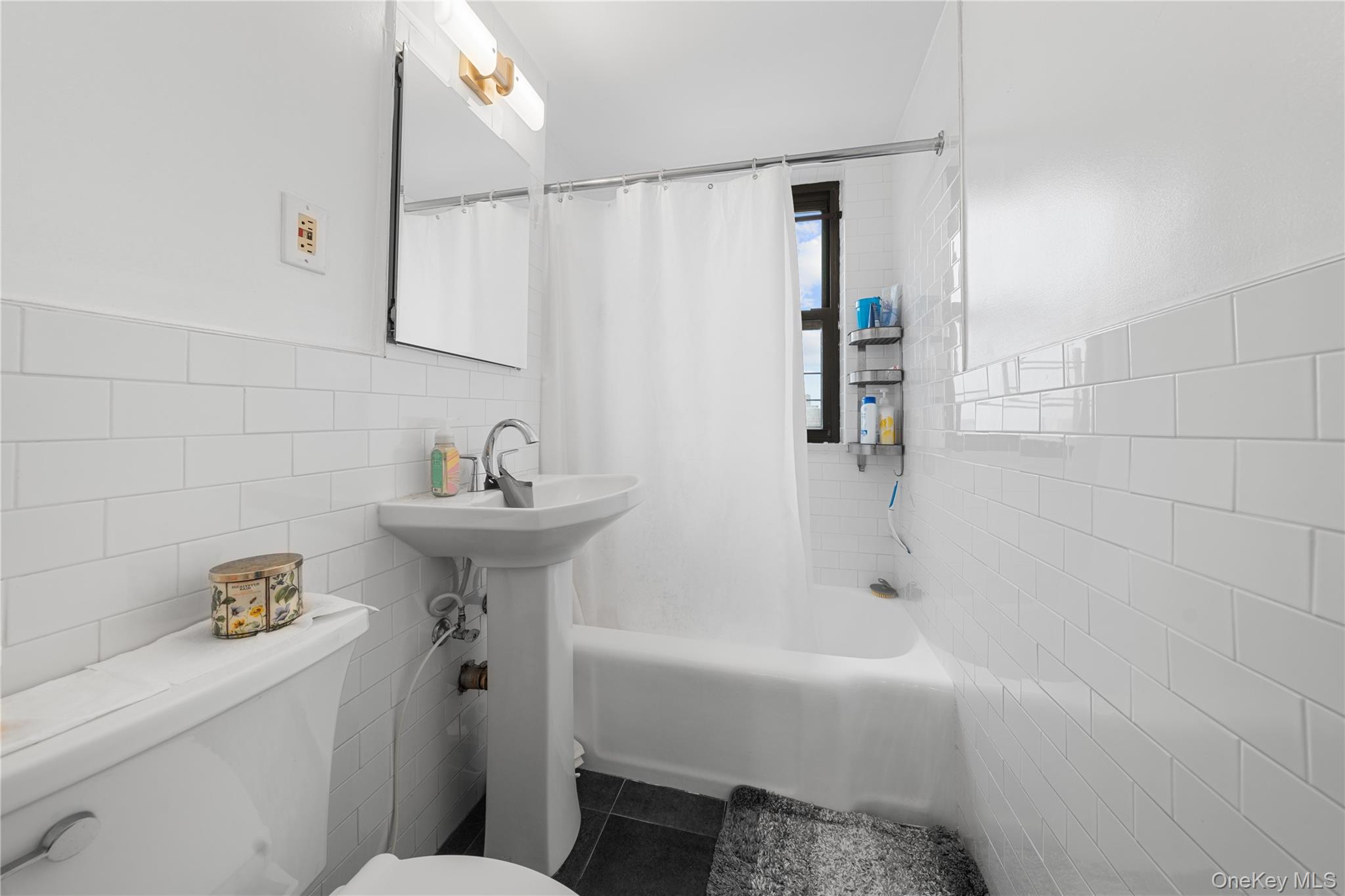 99-32 66th Road, Unit 5K Queens, NY 11374 - Photo 16 of 20 Bathroom with tile walls, shower / bathtub combination with curtain, and dark tile patterned floors