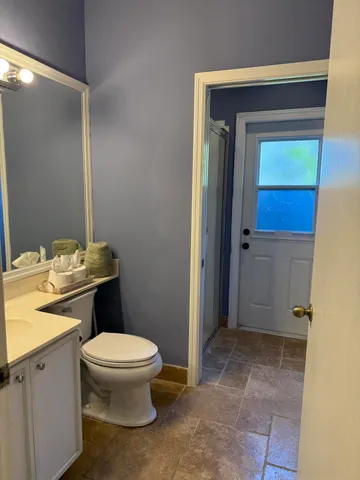a bathroom with a granite countertop sink toilet and mirror