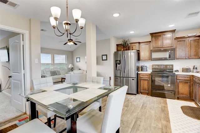 a kitchen with a table chairs stainless steel appliances and cabinets