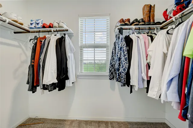 a view of walk in closet with clothes and shoes