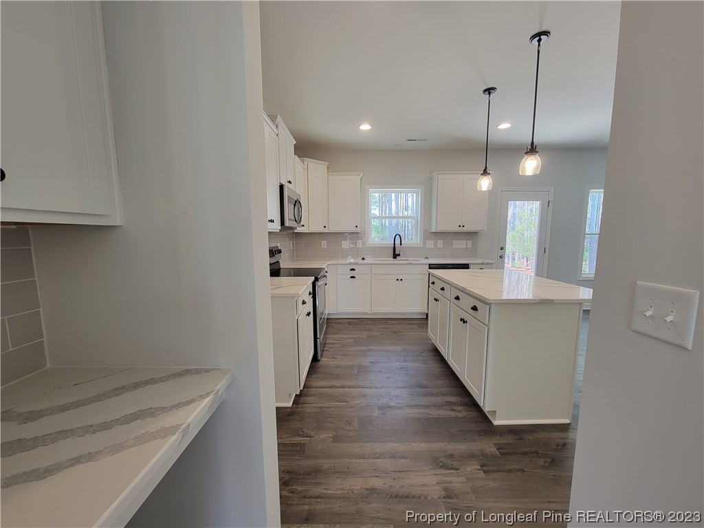 187 Timber Skip Drive Spring Lake, NC 28390 - Photo 4 of 20 a kitchen with stainless steel appliances kitchen island granite countertop a sink a stove a refrigerator and white cabinets