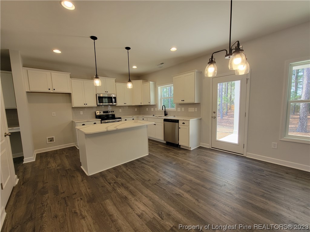 187 Timber Skip Drive Spring Lake, NC 28390 - Photo 5 of 20 a kitchen with stainless steel appliances granite countertop wooden floors and white cabinets