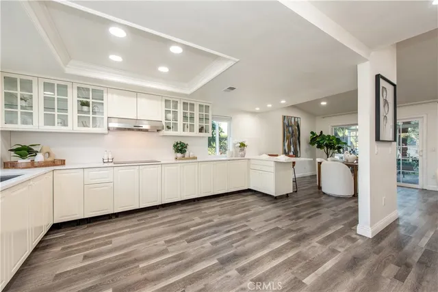 a large white kitchen with kitchen island a sink a center island and stainless steel appliances
