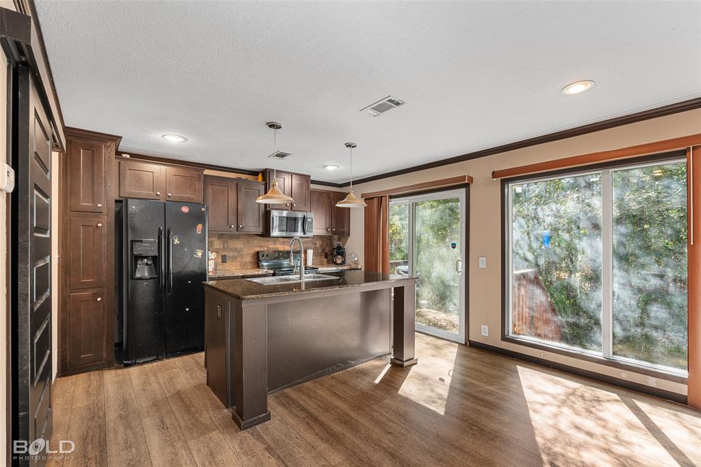 9489 Capps City Road Rodessa, LA 71069 - Photo 18 of 34 a kitchen with stainless steel appliances granite countertop a refrigerator a stove top oven a sink and dishwasher with wooden floor