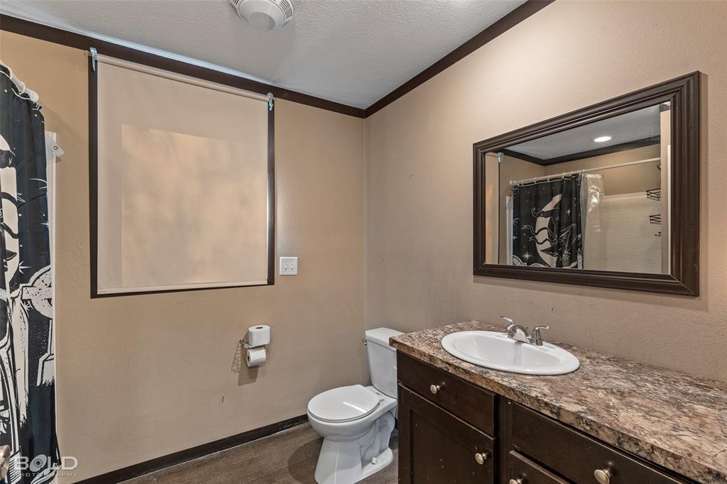 9489 Capps City Road Rodessa, LA 71069 - Photo 31 of 34 a bathroom with a granite countertop sink mirror vanity and toilet
