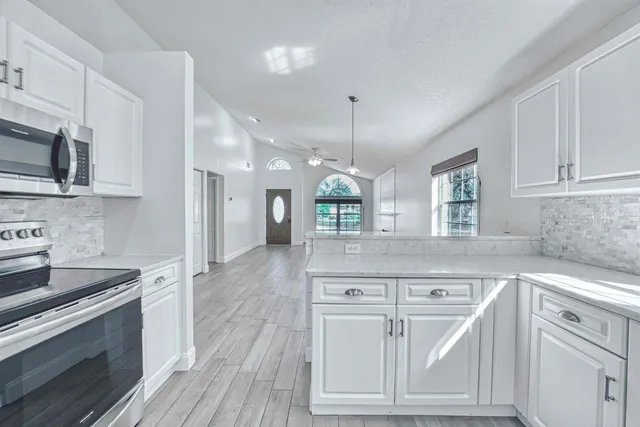 a large kitchen with cabinets wooden floor and stainless steel appliances