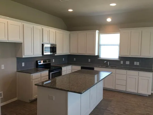 a kitchen with stainless steel appliances granite countertop a sink stove and microwave