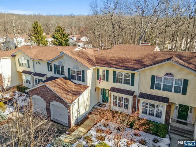 a front view of a house with a yard and large tree