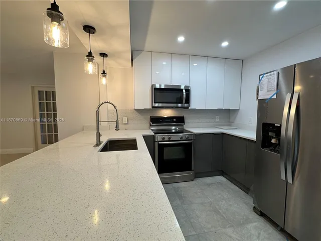 a kitchen with granite countertop a refrigerator and a stove top oven