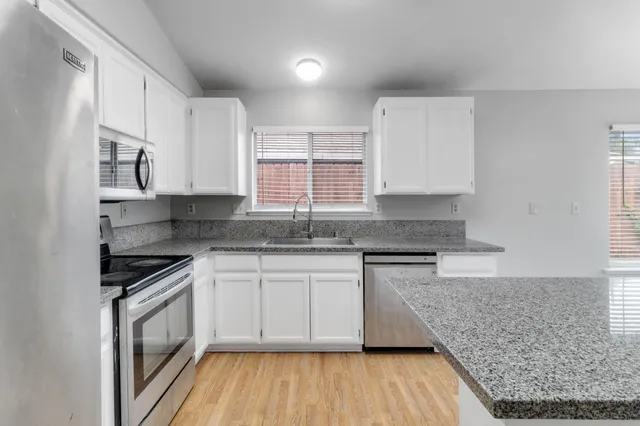 a kitchen with granite countertop wooden cabinets and a stove