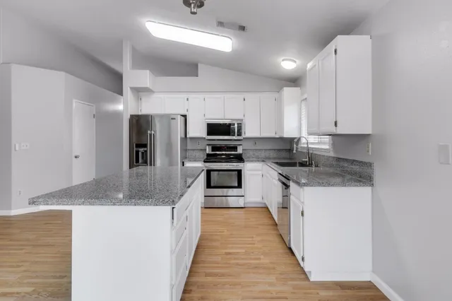 a large kitchen with stainless steel appliances granite countertop a stove top oven a sink and dishwasher