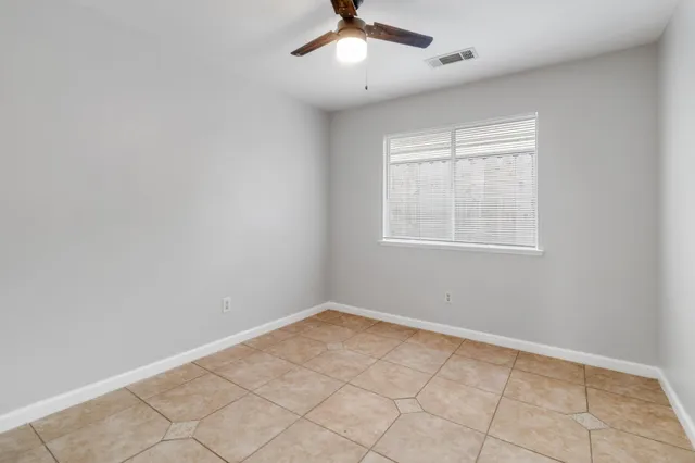 an empty room with windows and fan
