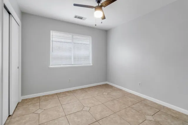 an empty room with windows and fan