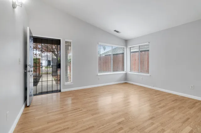 a view of an empty room with wooden floor and a window