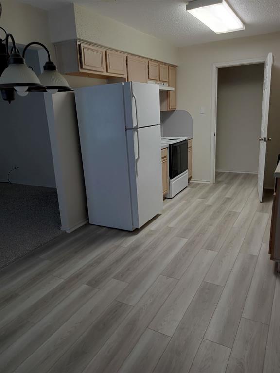 113 South Summit Street Red Oak, TX 75154 - Photo 3 of 4 a view of a refrigerator in kitchen and an empty room with wooden floor