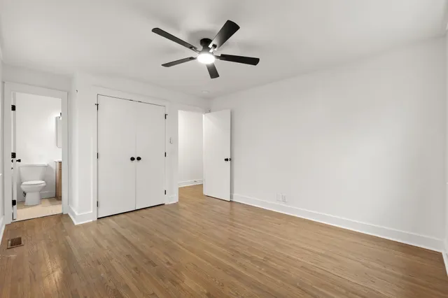 an empty room with wooden floor and a ceiling fan