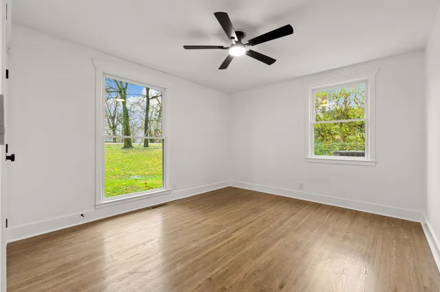 a view of an empty room with a window and wooden floor