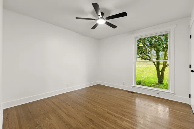 an empty room with a window and a ceiling fan