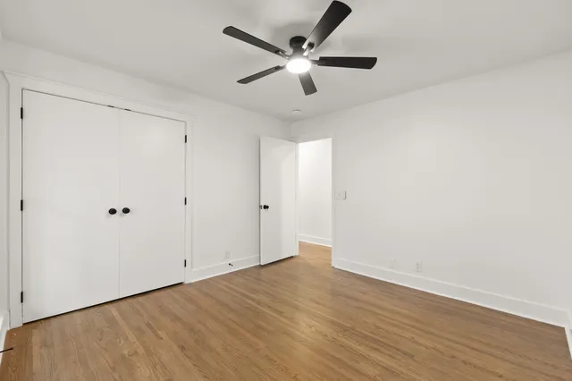 an empty room with wooden floor and ceiling fan