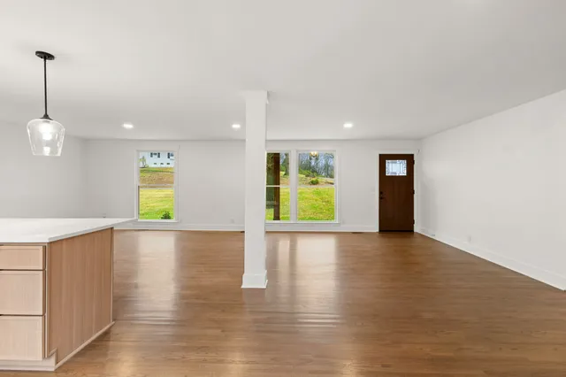 a view of empty room with window and wooden floor