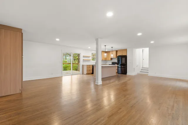 a view of an empty room with a kitchen and a window