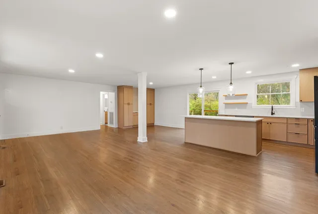 a large kitchen with kitchen island a stove a sink dishwasher and a refrigerator with wooden floor