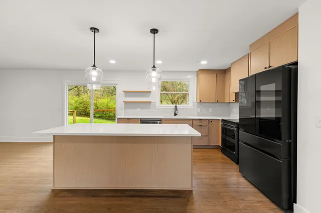 a kitchen with stainless steel appliances granite countertop a sink a stove and a wooden floors