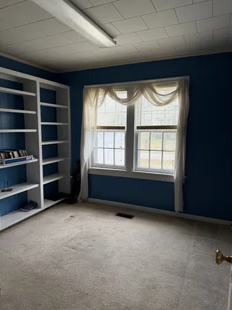 a view of an empty room with a window and a kitchen