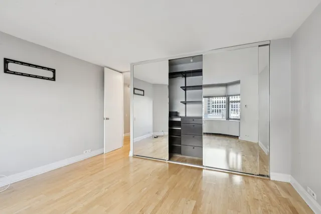 an empty room with wooden floor cabinet and windows