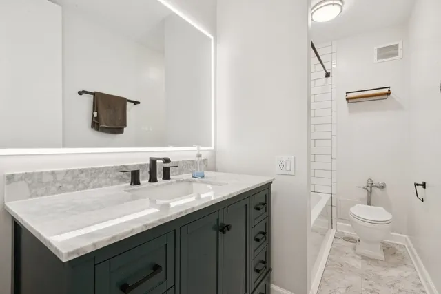 a bathroom with a granite countertop sink a toilet and a mirror