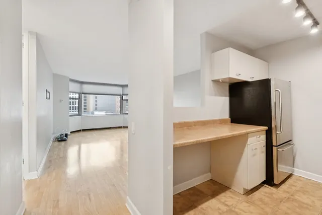 a view of a kitchen with refrigerator and wooden floor