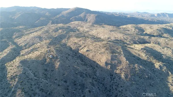a view of a dry yard with mountains in the background