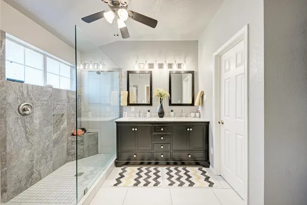 a bathroom with a double vanity sink mirror and shower