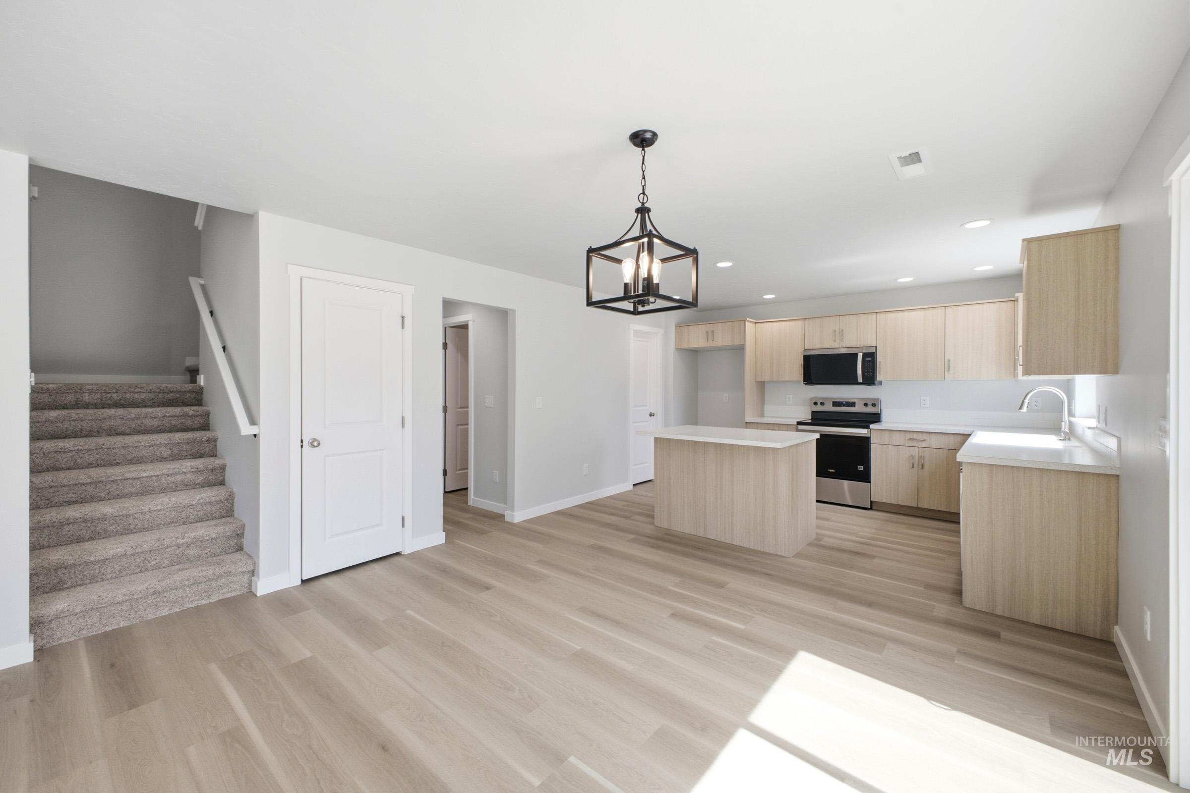 13336 Bank Street Caldwell, ID 83607 - Photo 7 of 24 Open-concept living space with light wood-finish flooring, a contemporary kitchen island, and a modern pendant light fixture